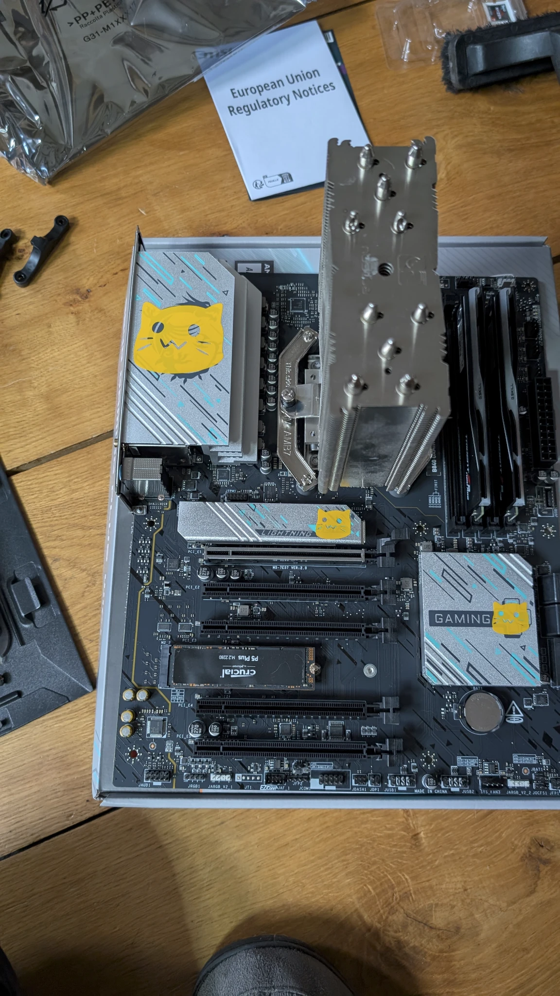 Photo of a motherboard on a box but Blobcat decal stickers have been placed on various parts covering branding and original decals. They are bright yellow and adorable.
