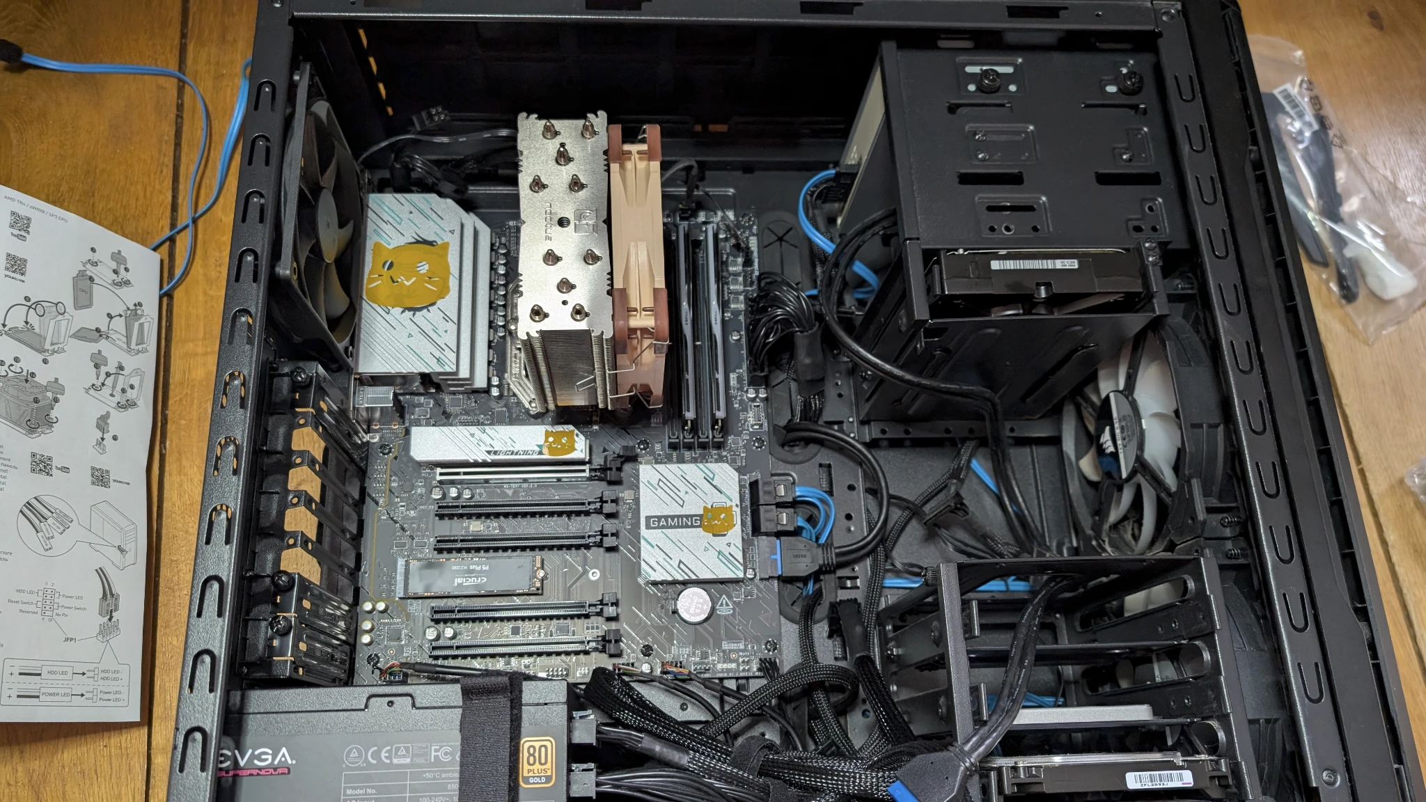 Photo of a built PC internals showing blobcat stickers on the motherboard. The PC is on it's side and the GPU is missing.