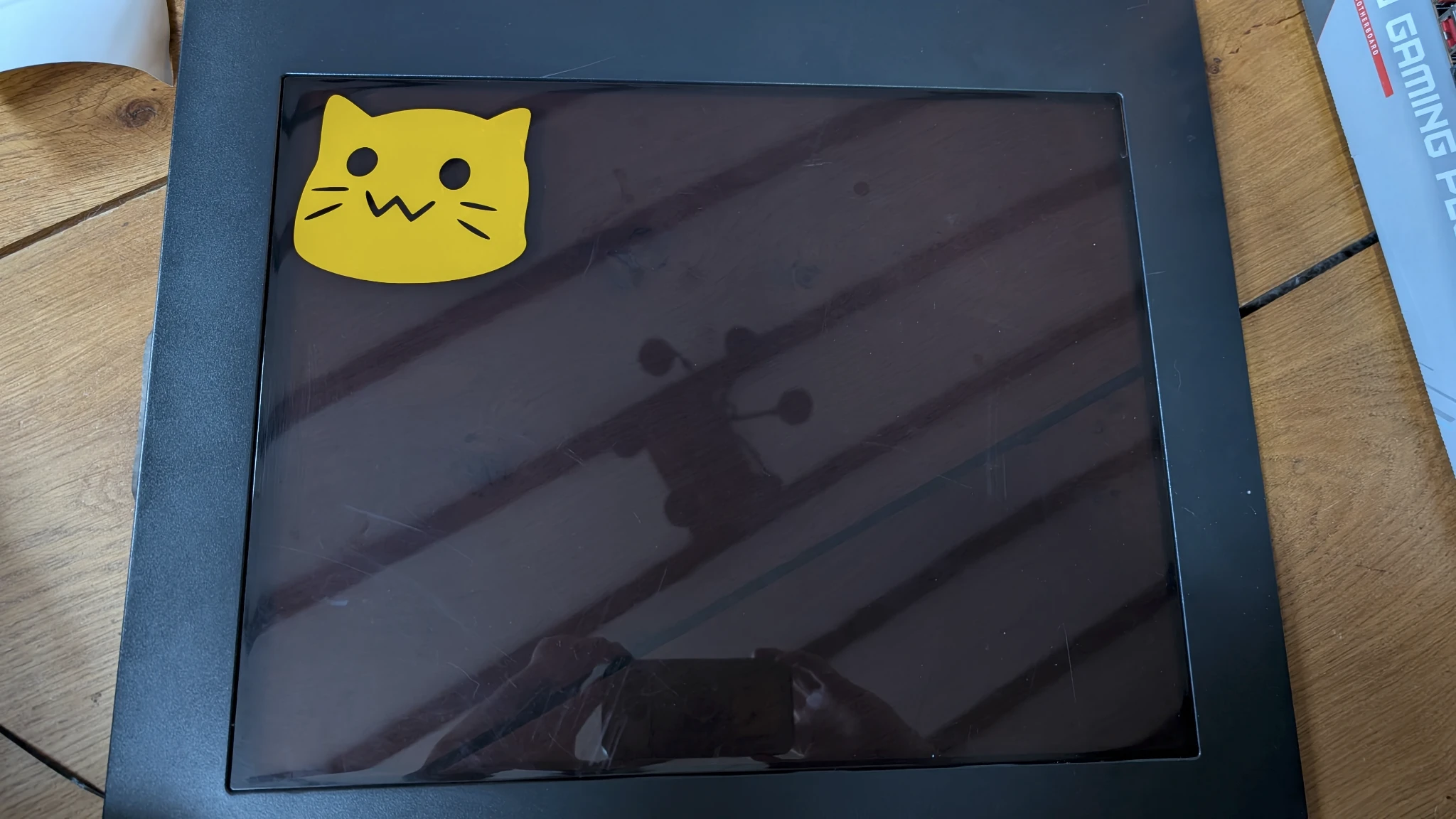 Photo of a PC case side on the floor, it has a glass / platic window, in the corner of the window is a Blobcat sticker.