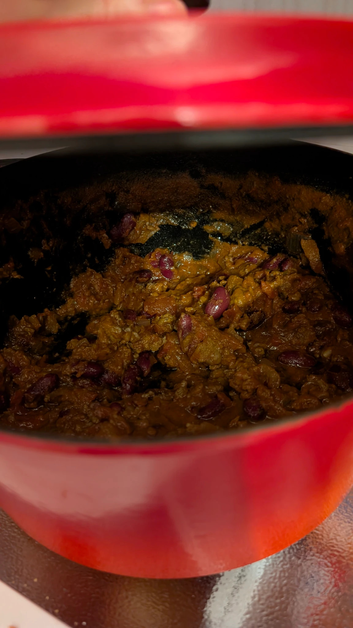 Photo of a red pot of chilli the lid is just opened slightly to photograph the inside.