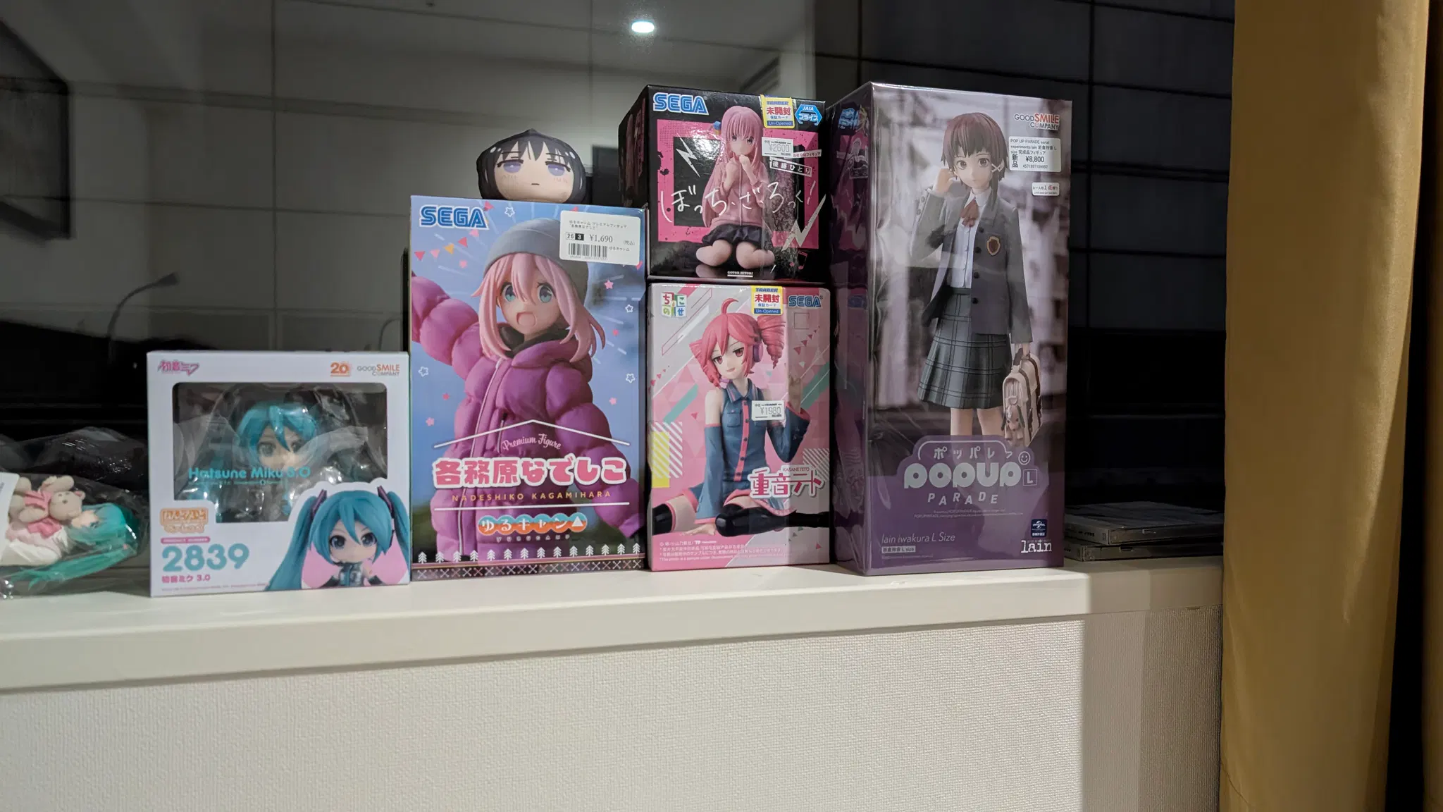 A stack of anime figures on a window sill.